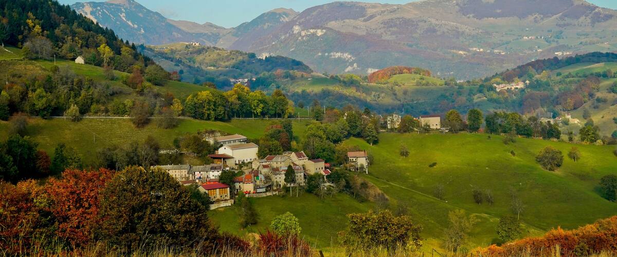 A valley with houses and mountains in the background.