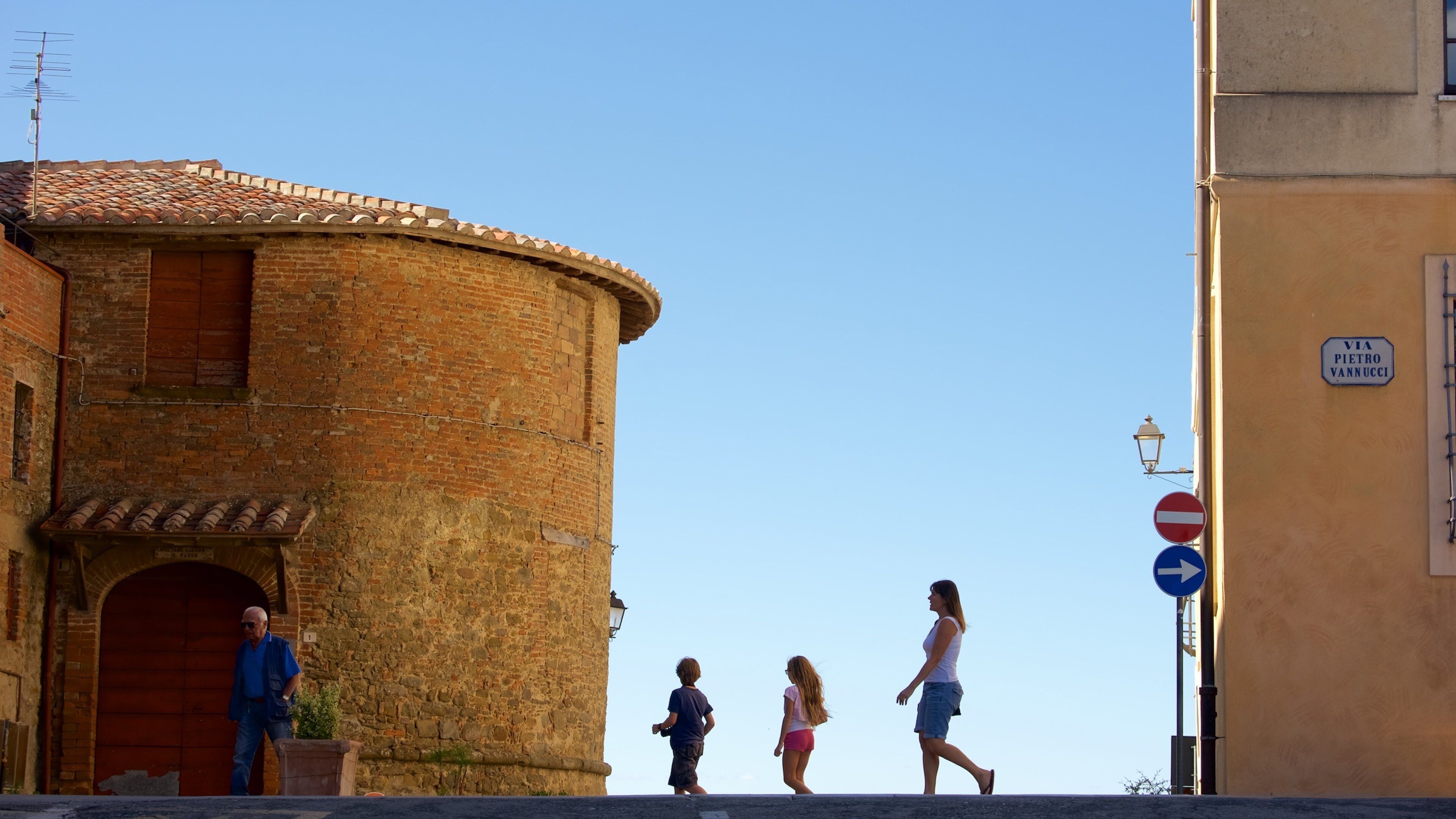 Una torre de ladrillo histórica, una señal de calle y peatones.