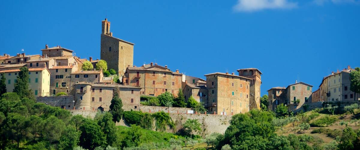 A historic town with stone buildings, a prominent tower, and lush greenery.
