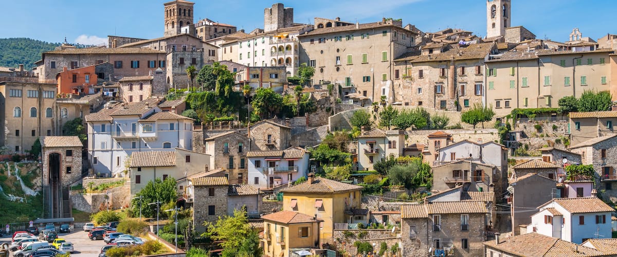 A historic town with stone buildings, a prominent tower, and a hillside backdrop.