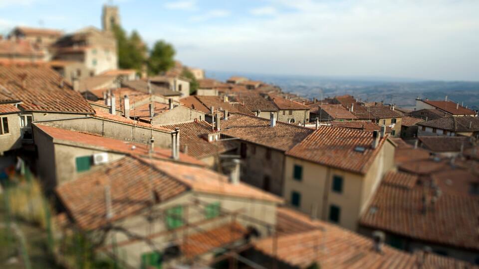 A town with terracotta-roofed buildings and a distant church.