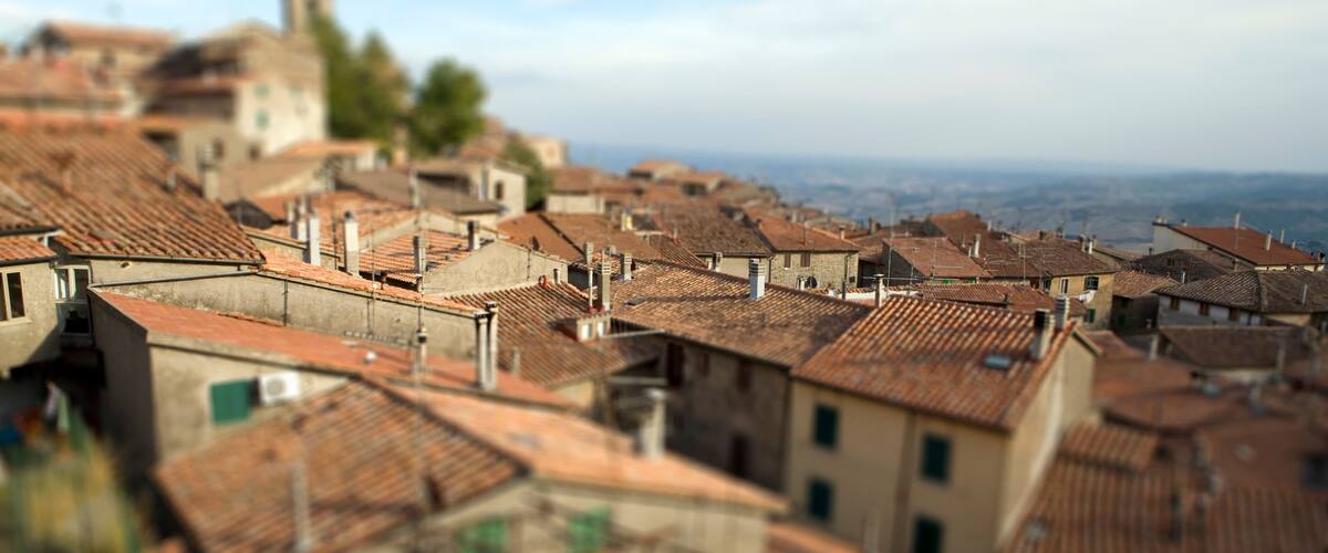A town with terracotta-roofed buildings and a distant church.
