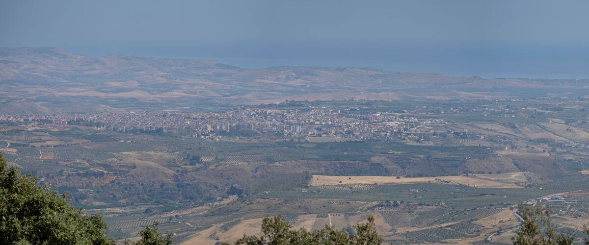 A panoramic view of a city with rolling hills and a distant coastline.