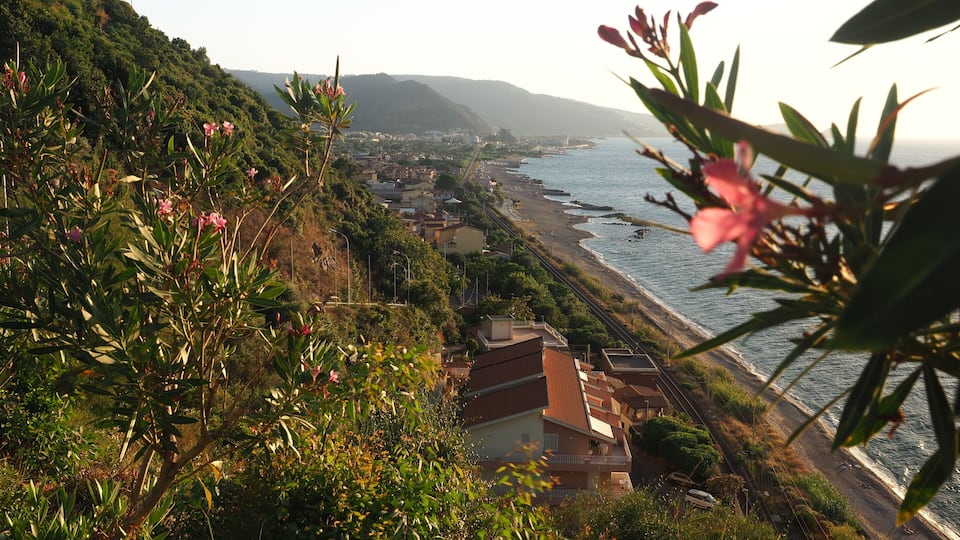 A coastal town with a hillside, a beach, and a railway track.