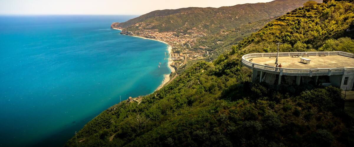 A coastal landscape with a circular viewing platform overlooking a beach and the sea.