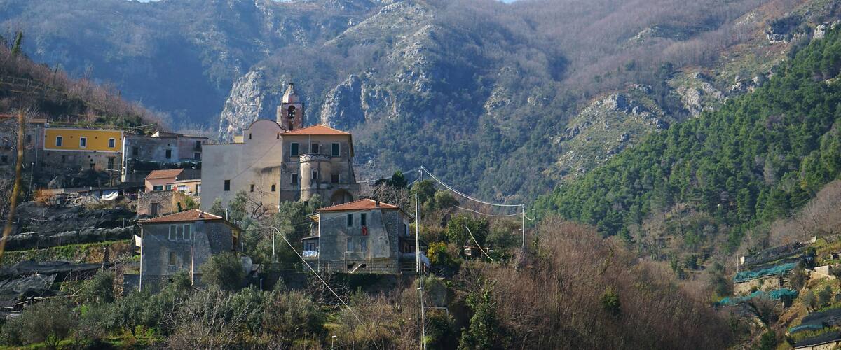 A mountainous village with a prominent church, houses, and lush greenery.