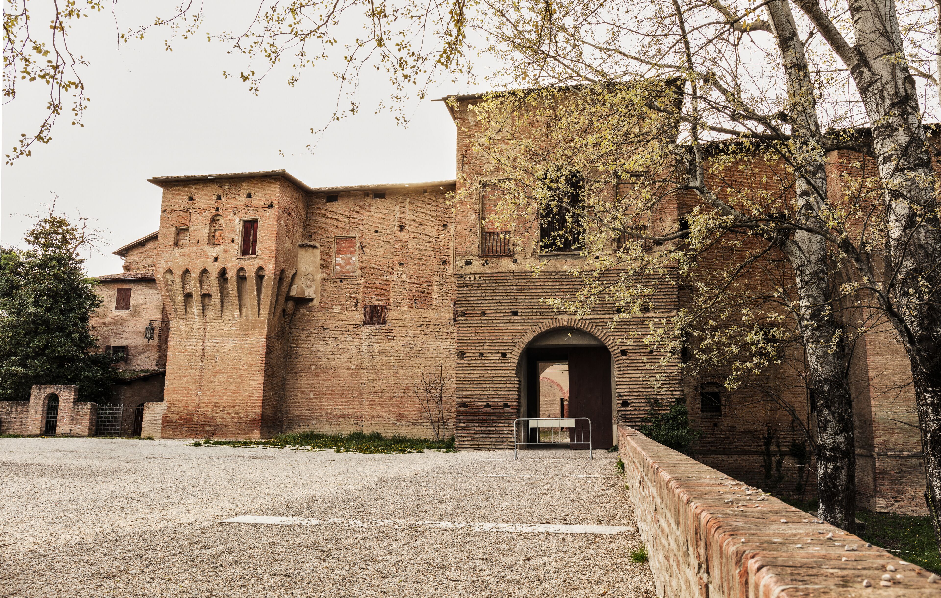 A historic brick building with arched doorways and a gravel courtyard.