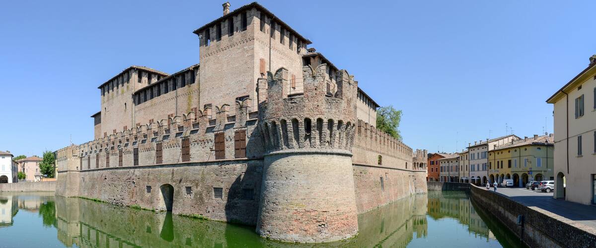 A historic castle with a moat, surrounded by traditional buildings.