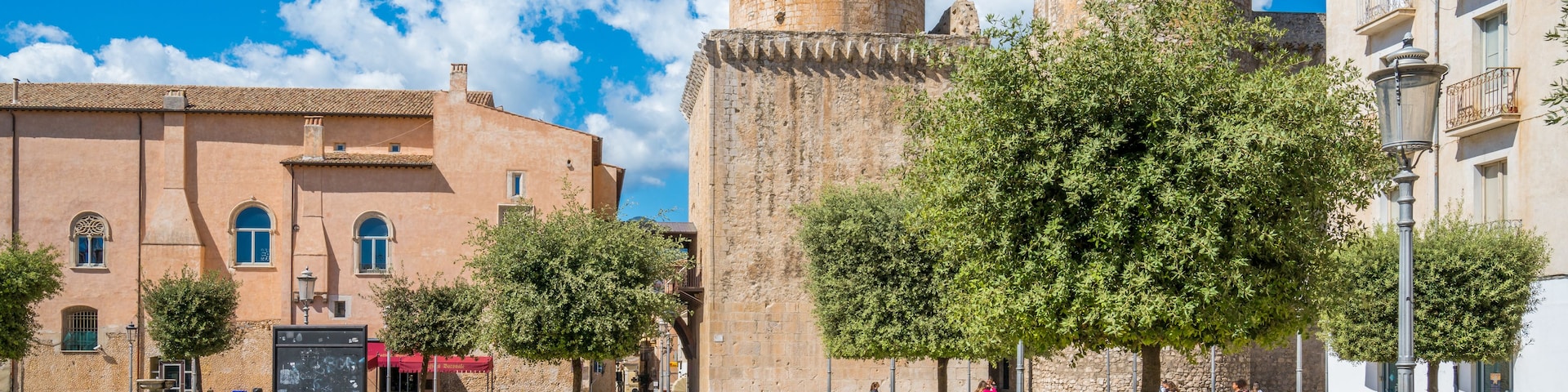 Una plaza histórica con una imponente torre de piedra, un sendero adoquinado y edificios tradicionales.