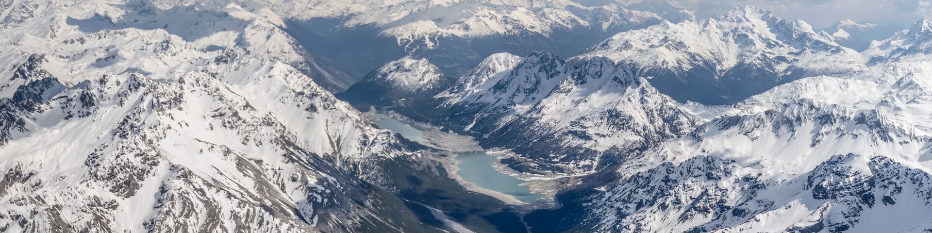 Una cordillera nevada con un valle glaciar y un lago.