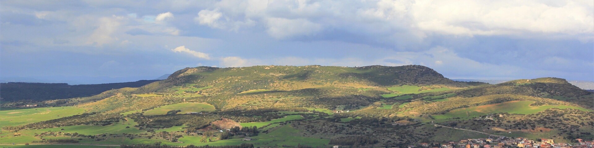 Colinas ondulantes, un pueblo pequeño y un cielo nublado.