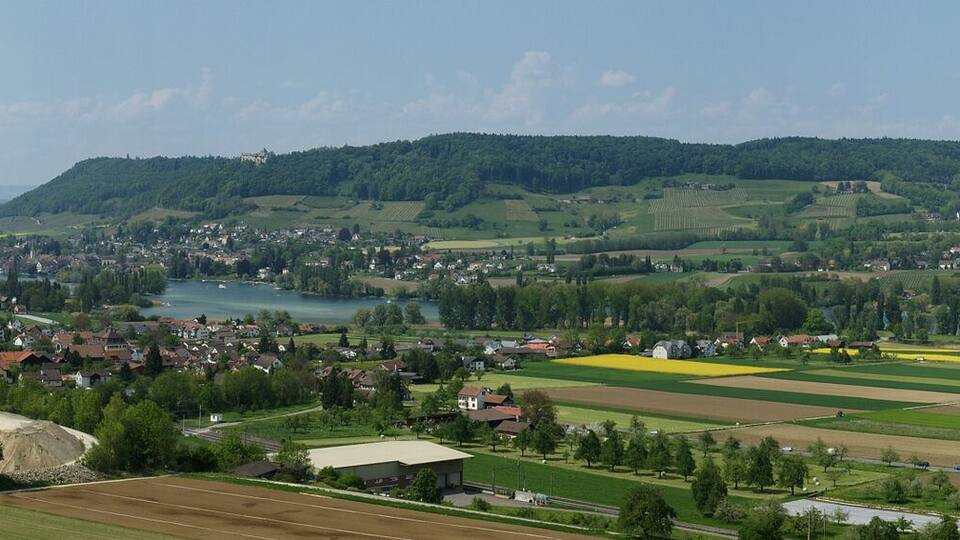 A river flowing through a town surrounded by green hills and fields.