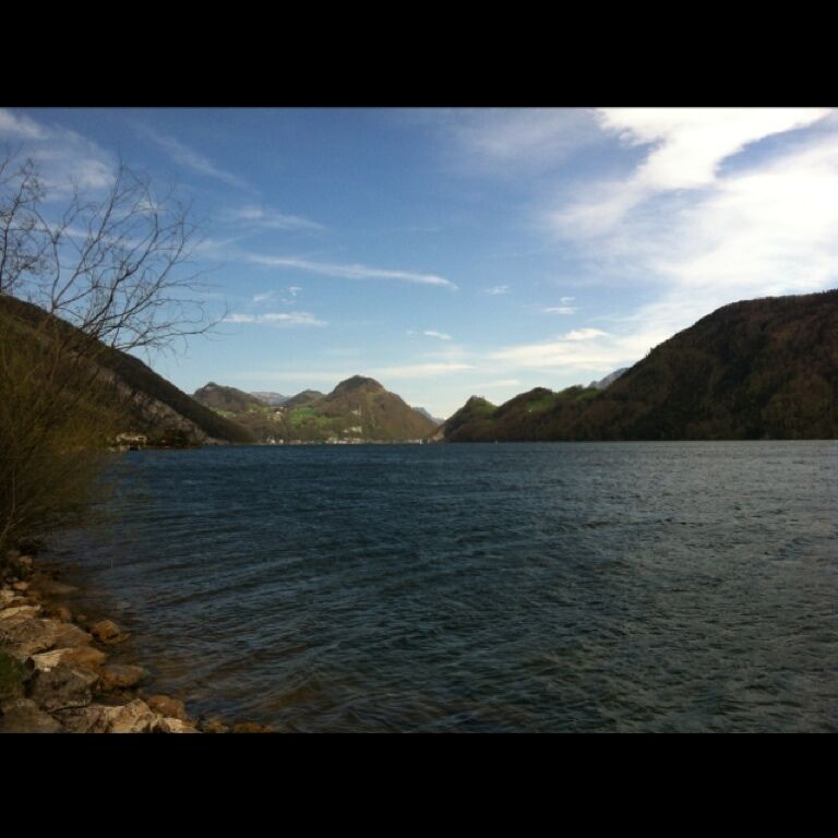 A calm lake surrounded by rocky hills and sparse vegetation.