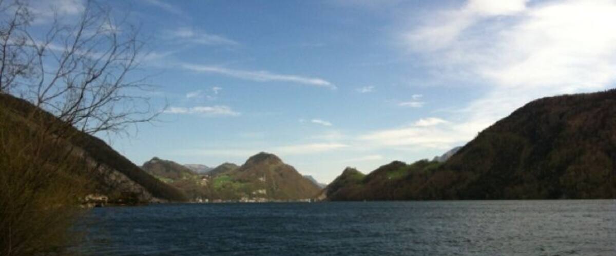 A calm lake surrounded by rocky hills and sparse vegetation.