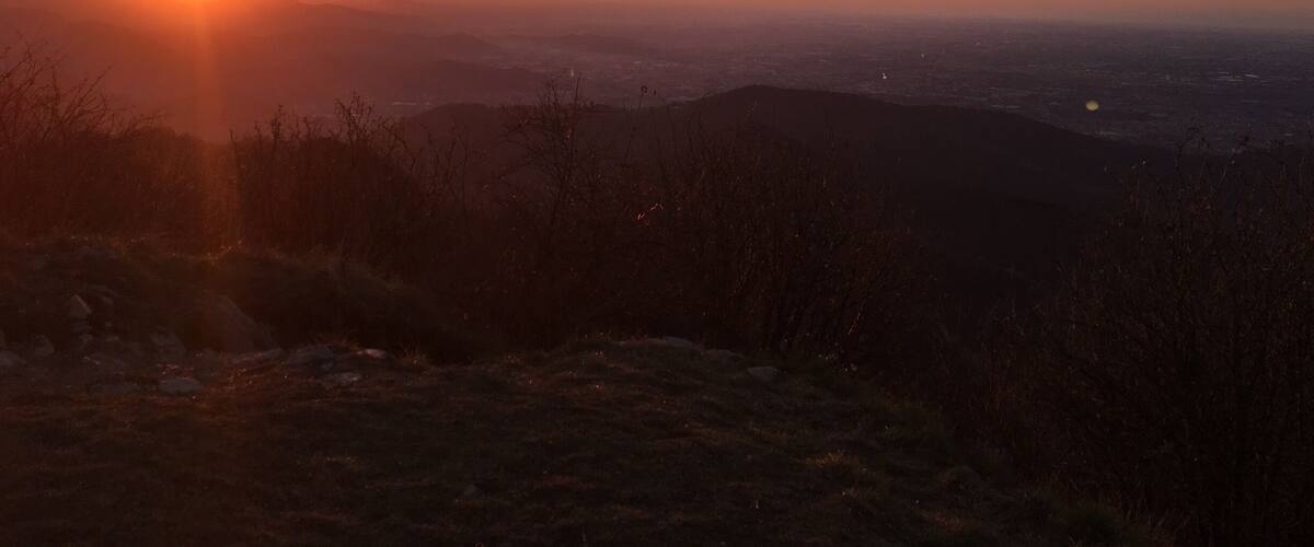 A sunset over a mountainous landscape with a city in the distance.