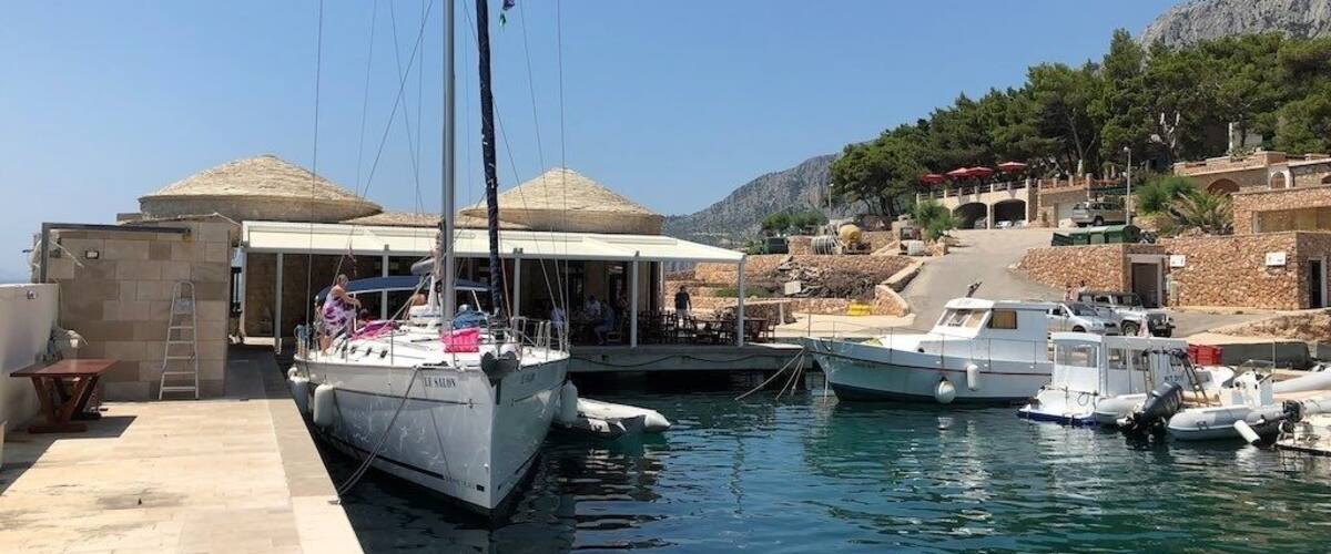 A marina with boats docked, a covered area, and a mountainous backdrop.