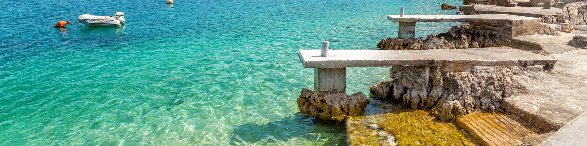 A coastal town with clear turquoise waters, boats, and rocky shorelines.
