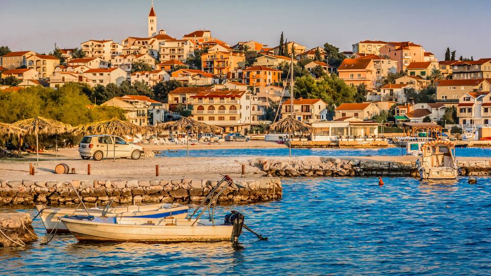 A coastal town with buildings, a boat, and a lighthouse.