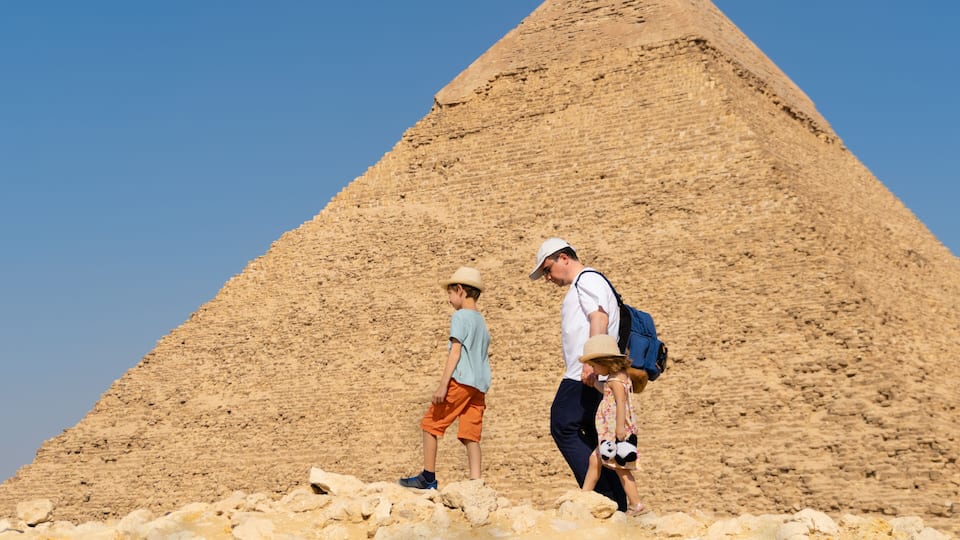 A large pyramid with tourists walking around it.