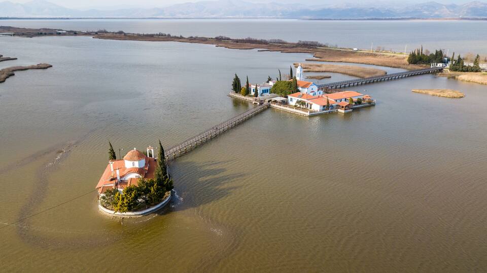 An aerial view of a lake with a small island featuring a church and residential buildings.