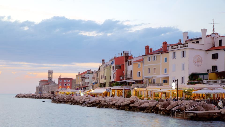 A coastal town with colorful buildings, a historic tower, and a rocky breakwater.