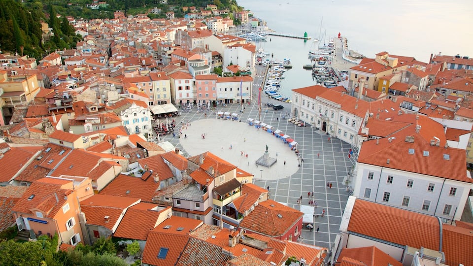 A coastal town with red-tiled roofs, a central square, and a marina with boats.