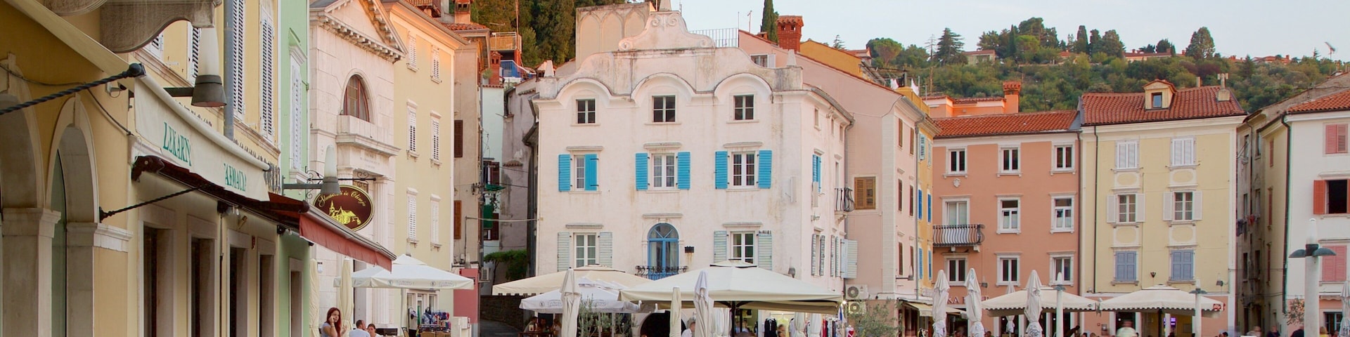 Uma praça com cafés, uma fonte e edifícios históricos.