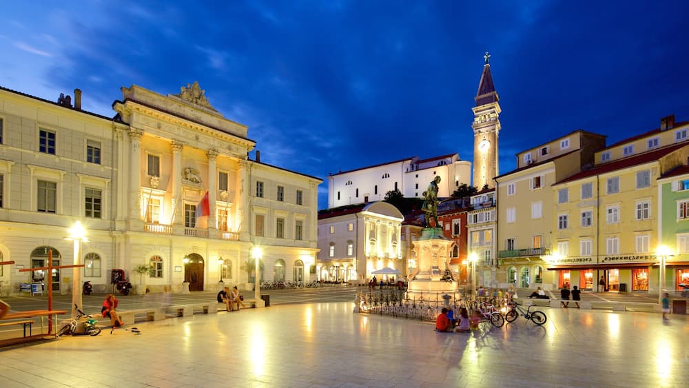 Piran mettant en vedette scĂšnes de nuit et square ou place aussi bien que important groupe de personnes