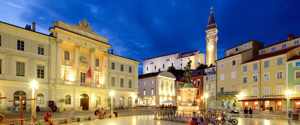 A historic square with ornate buildings, a clock tower, and a statue.