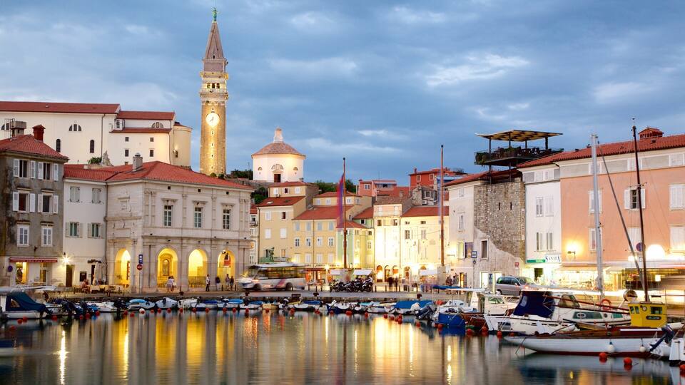 A waterfront with historic buildings, a clock tower, and boats docked in the harbor.
