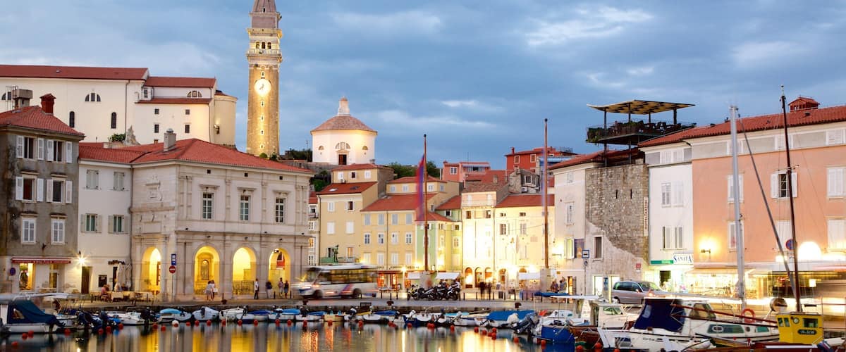 A waterfront with historic buildings, a clock tower, and boats docked in the harbor.
