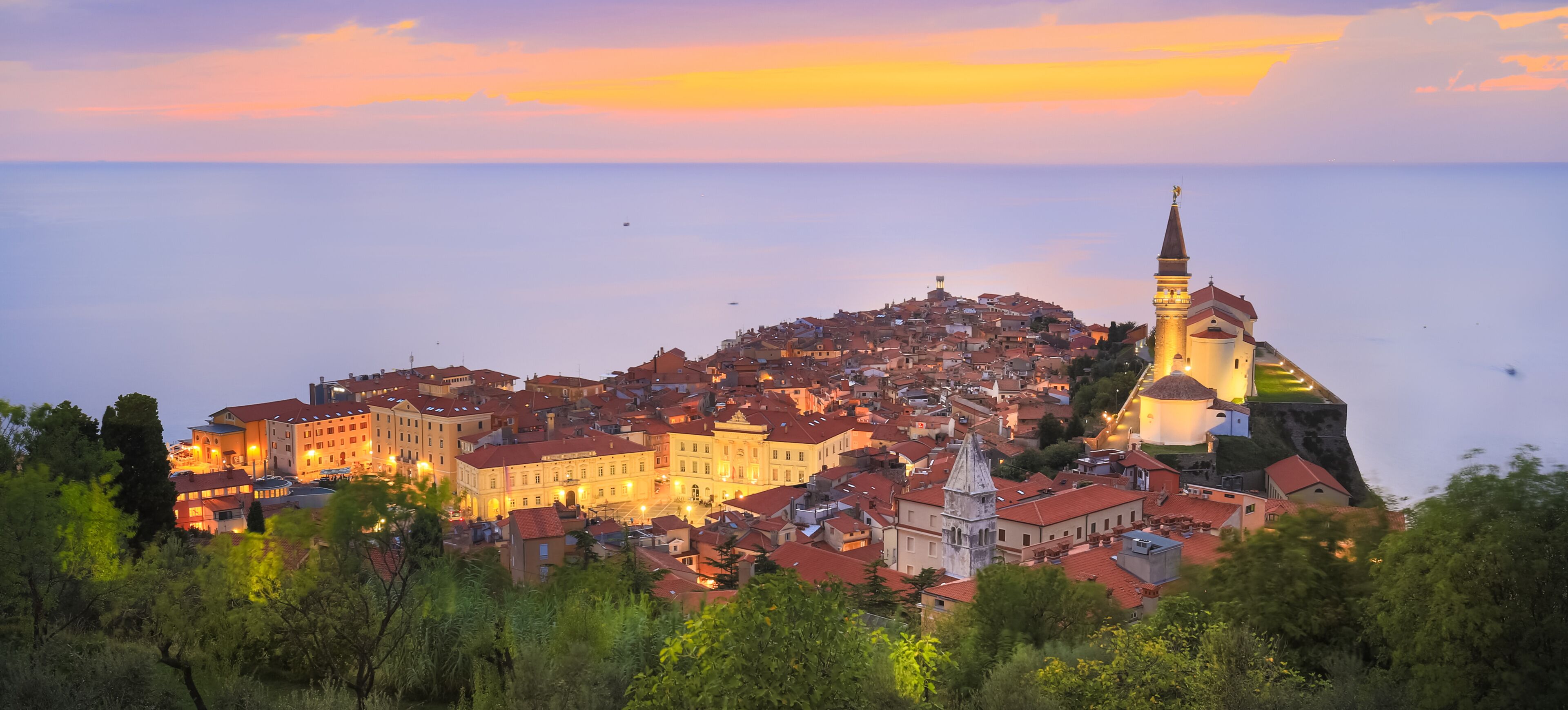 A coastal town with a prominent church tower and a fortified structure overlooking the sea.