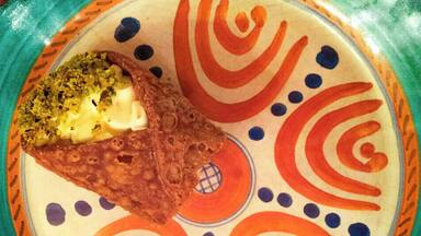 A plate with a piece of food, possibly a croquette, on a colorful patterned plate.