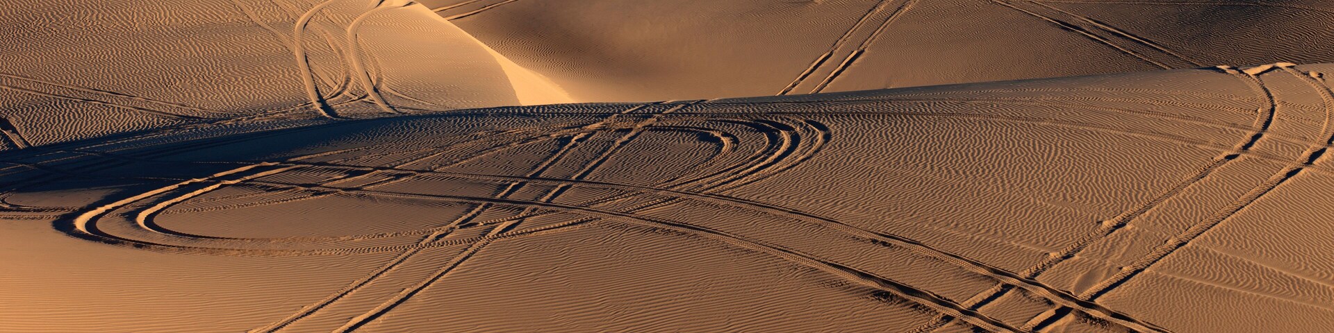 Sand dunes with wheel ruts and tire marks