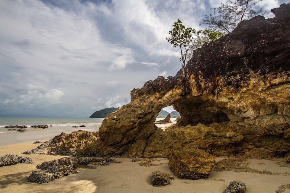 Formación rocosa natural con una abertura similar a una cueva en una playa.