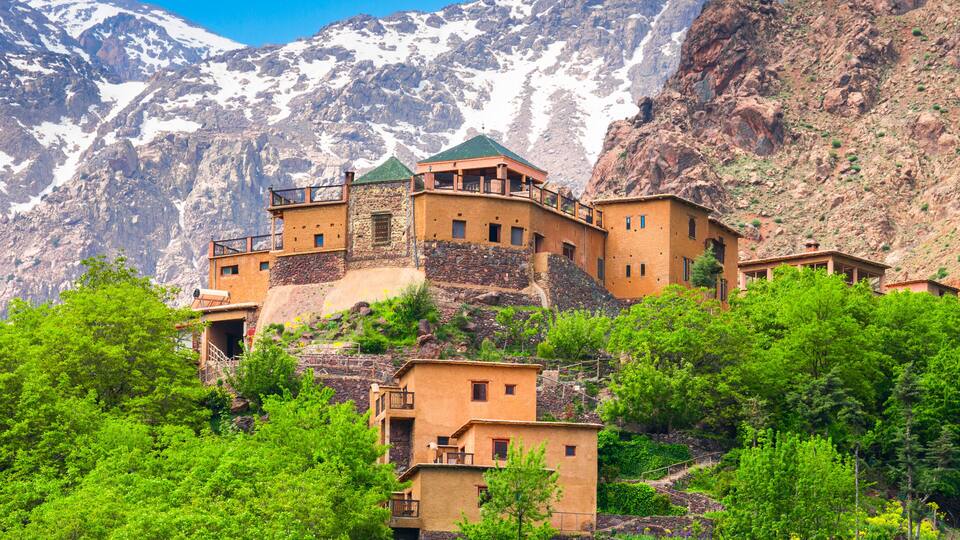 A mountain village with terraced buildings and snow-capped peaks in the background.