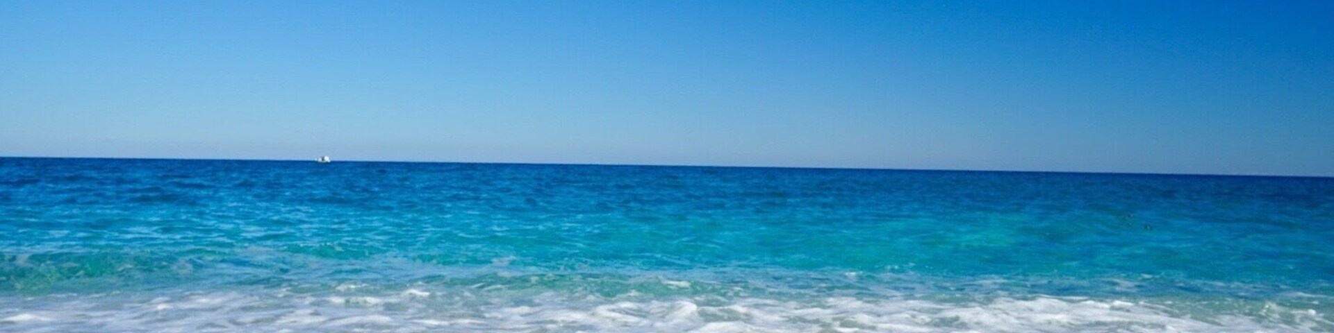 Una playa con aguas turquesas cristalinas y un litoral pedregoso.