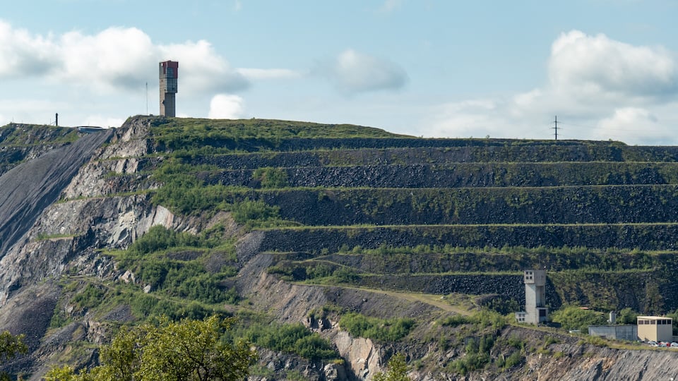 A mountainous landscape with terraced fields, a tall tower, and a smaller building.