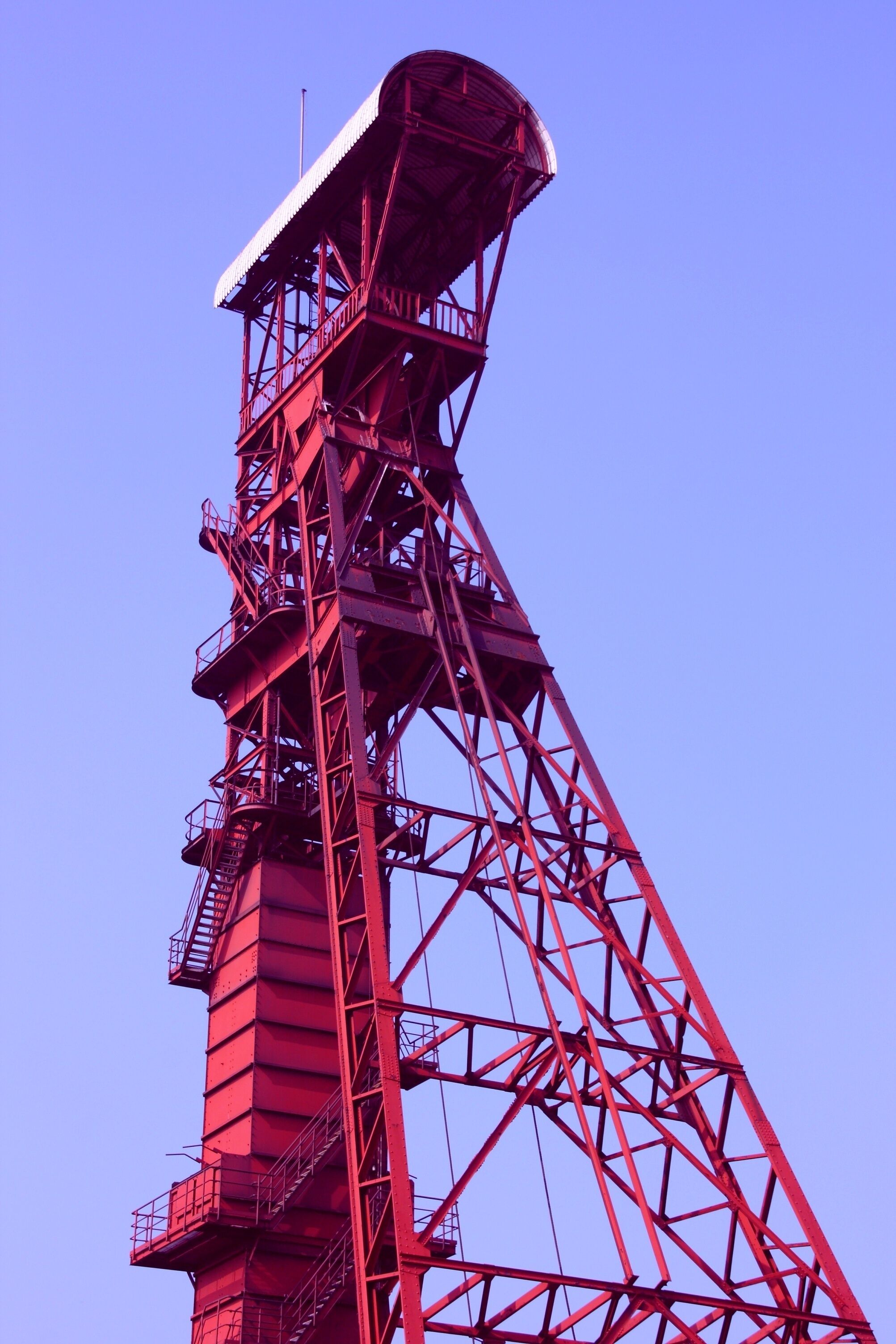 A tall red metal structure with a large open top, likely a crane or tower.
