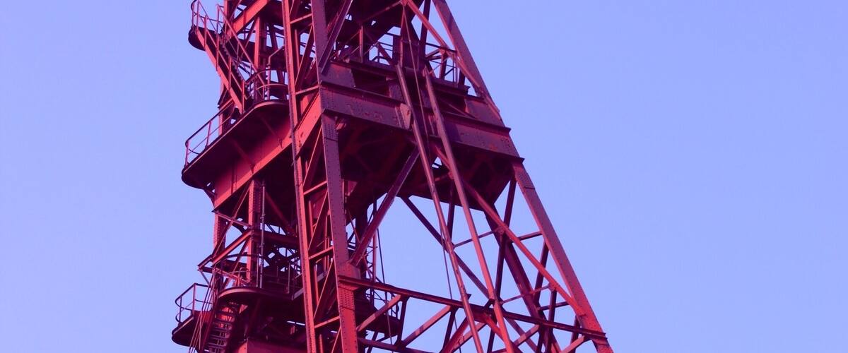 A tall red metal structure with a large open top, likely a crane or tower.