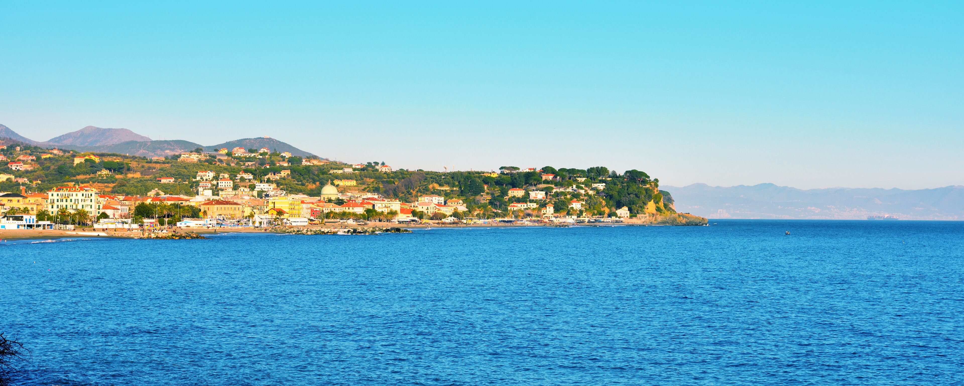 A coastal town with buildings on a hillside overlooking the sea.