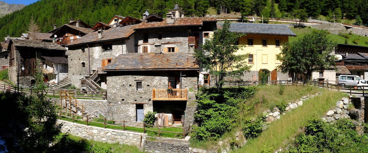 A mountain village with stone buildings, a bridge, and a flowing stream.