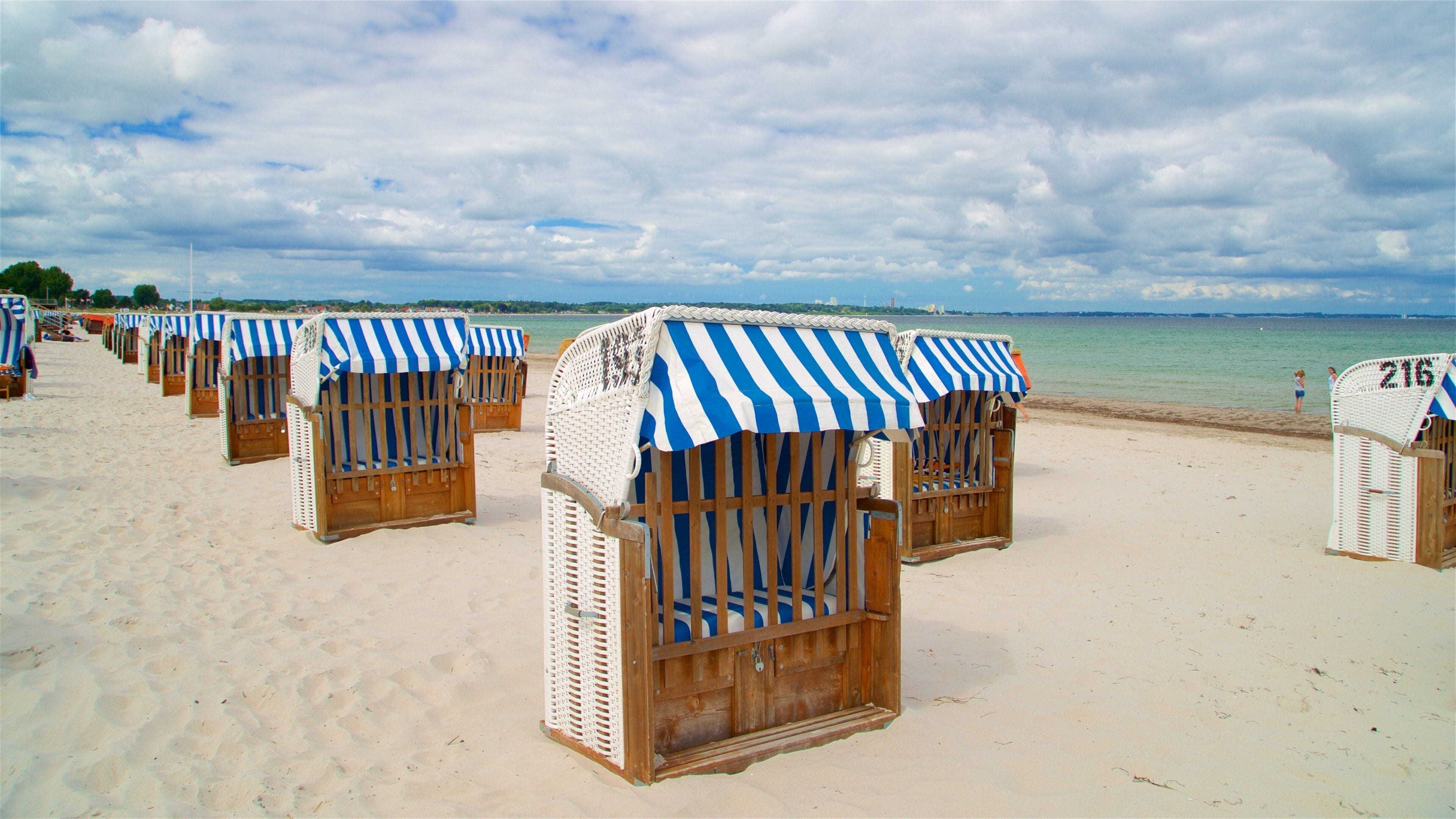 Beach huts with striped awnings on a sandy beach.