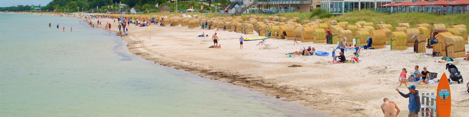 Una playa con gente, arena y edificios al fondo.