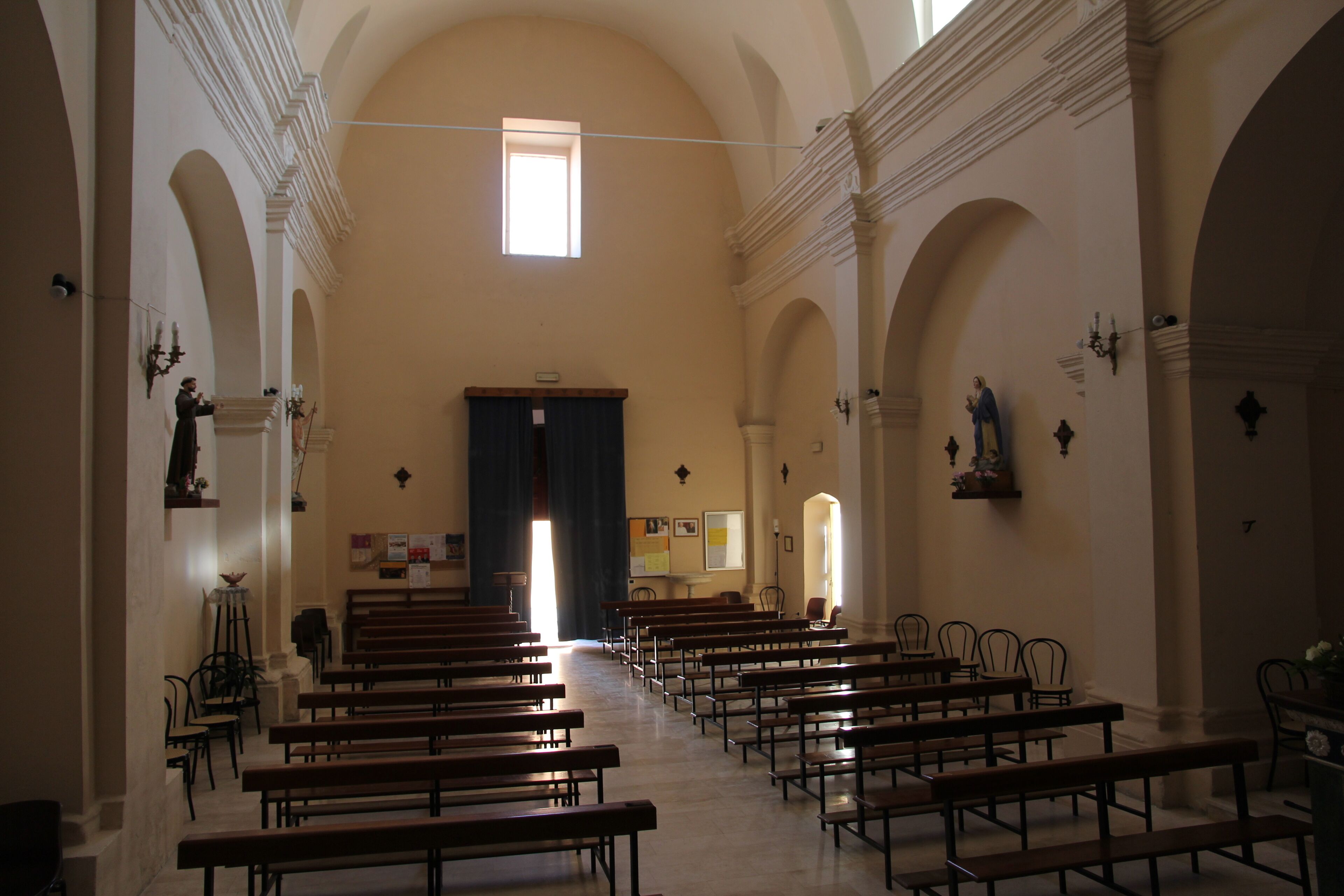 A church interior with rows of pews, arched ceilings, and a central altar.