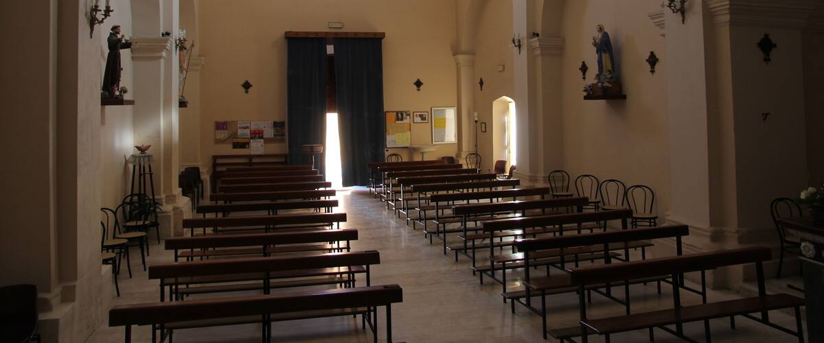 A church interior with rows of pews, arched ceilings, and a central altar.