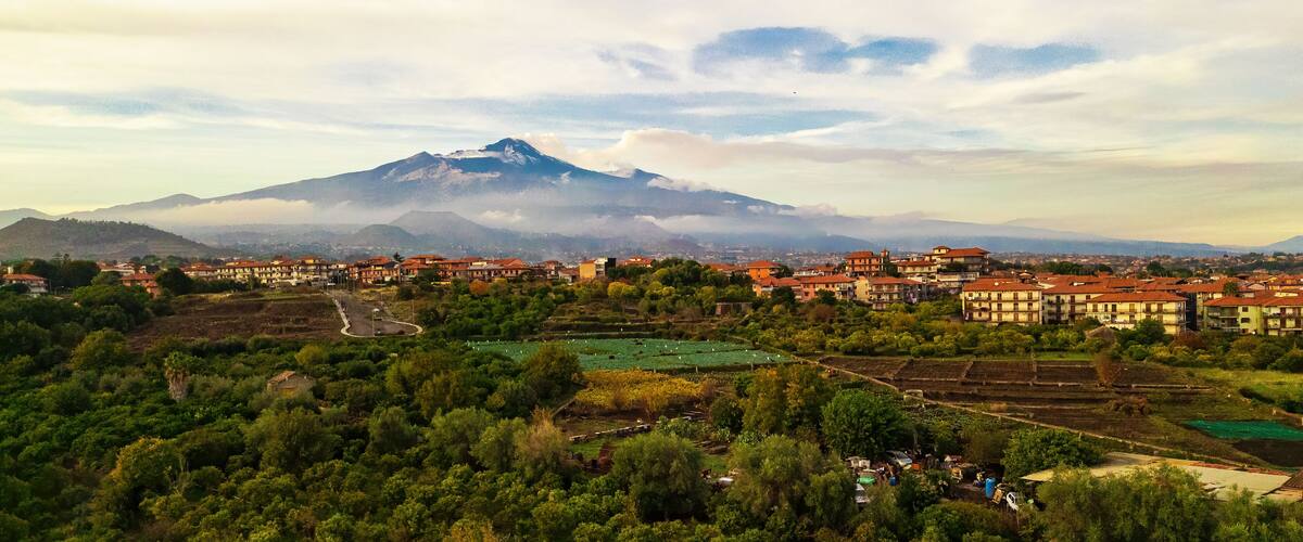 A mountain with a village in the foreground and a cloudy sky.