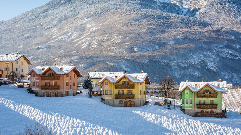 A snow-covered village with colorful houses and a mountain in the background.