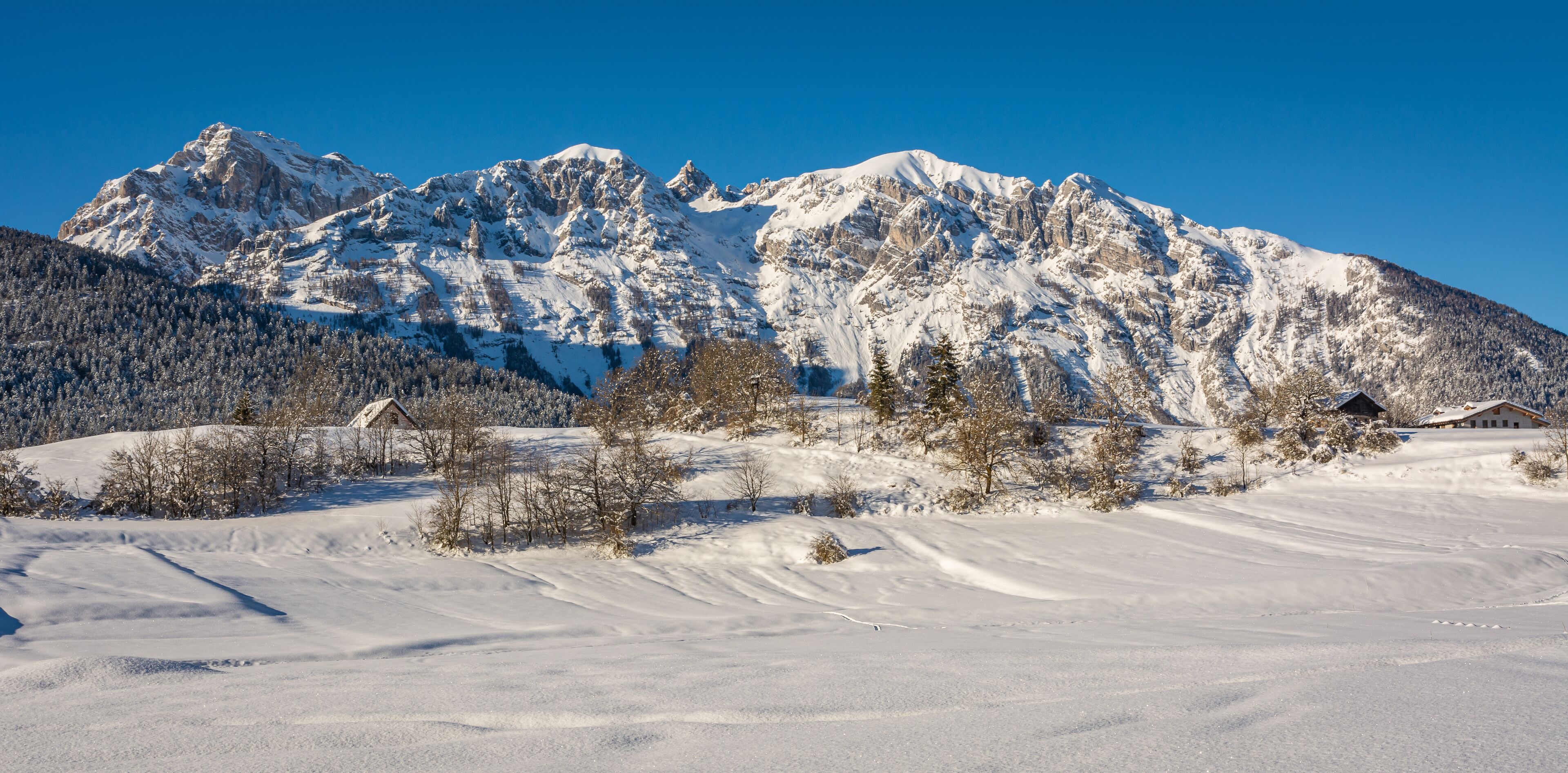 A snow-covered mountain range with a clear blue sky.