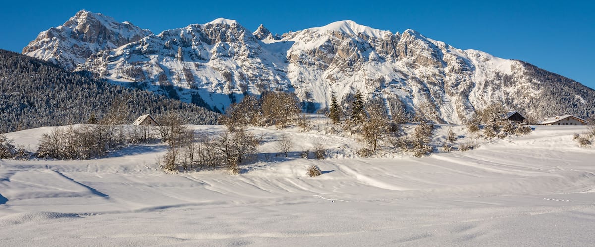 A snow-covered mountain range with a clear blue sky.